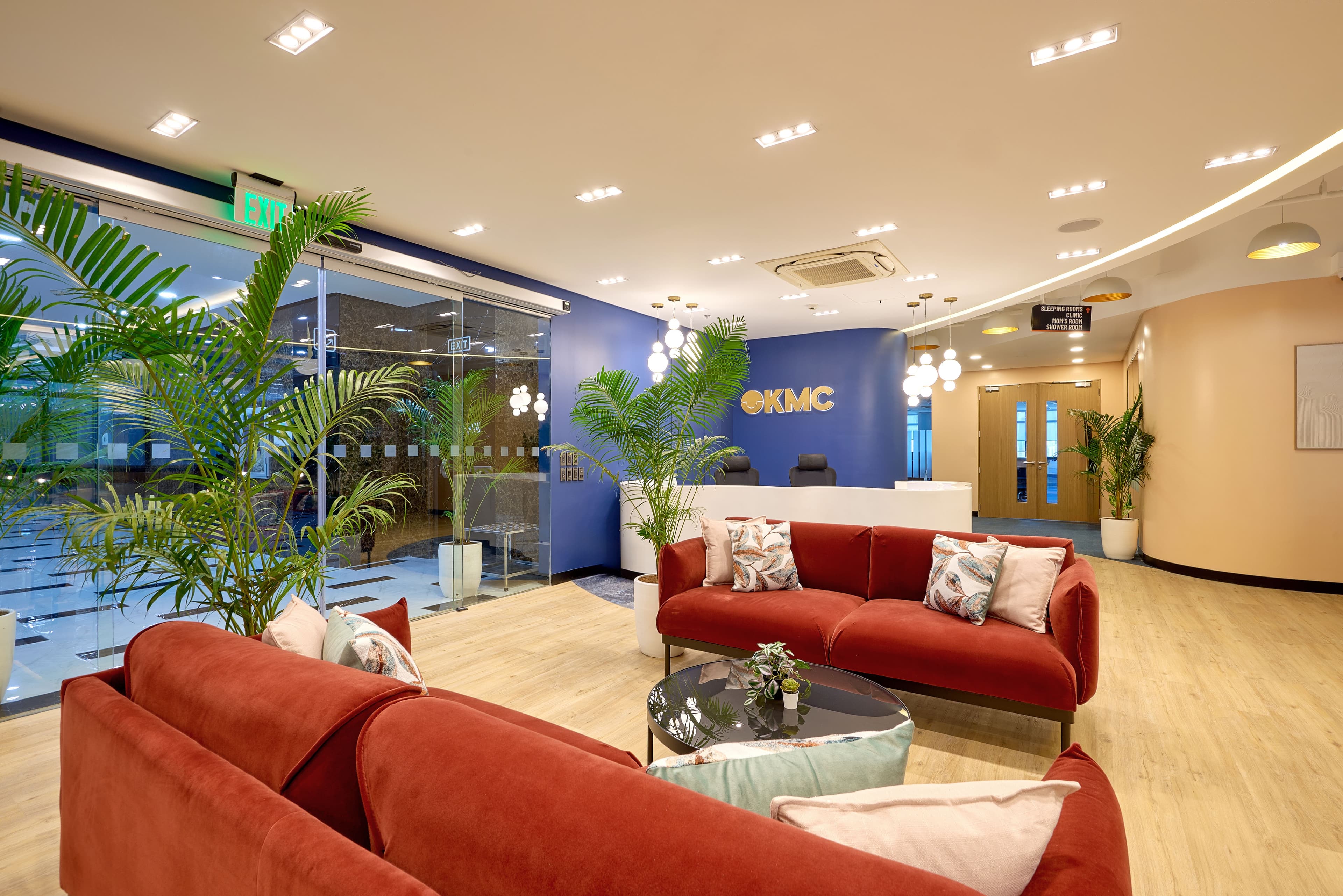 Modern KMC office lounge in Quezon City with red sofas, and a sleek white reception desk beside a glass-walled meeting room.