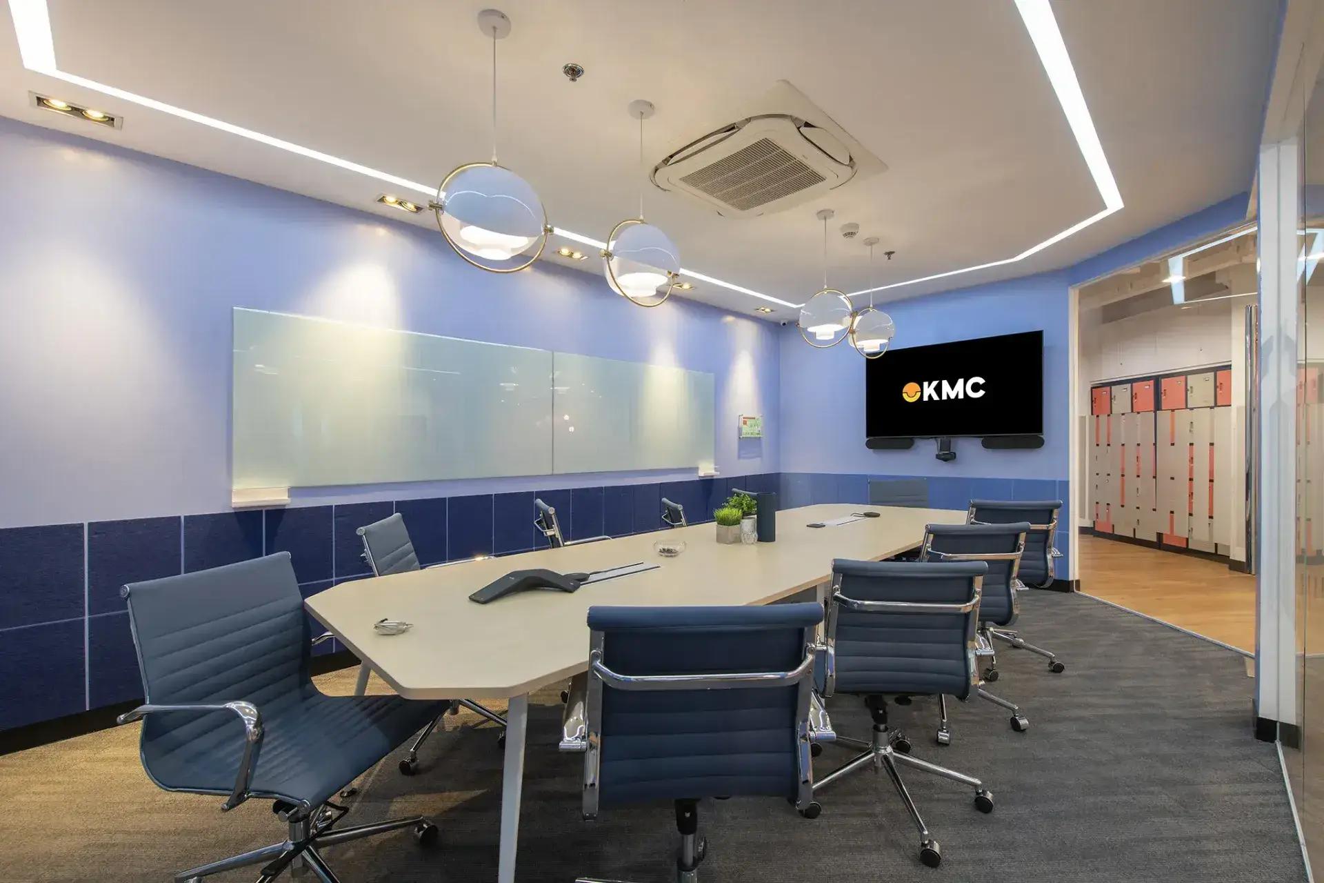 Modern office space in Cebu with blue chairs, light wood table, hanging globe lights, and glass white board. Modern office space in Cebu with blue chairs, light wood table, hanging globe lights, and glass white board.