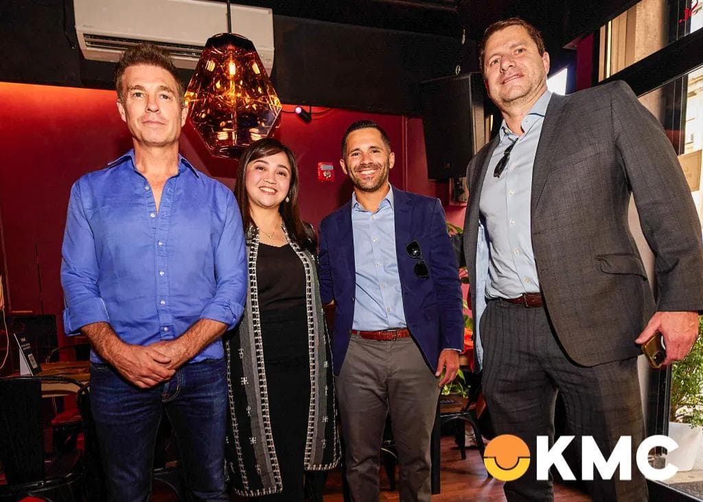Four professionals at KMC’s US Roadshow, highlighting business expansion through partnerships in a vibrant setting