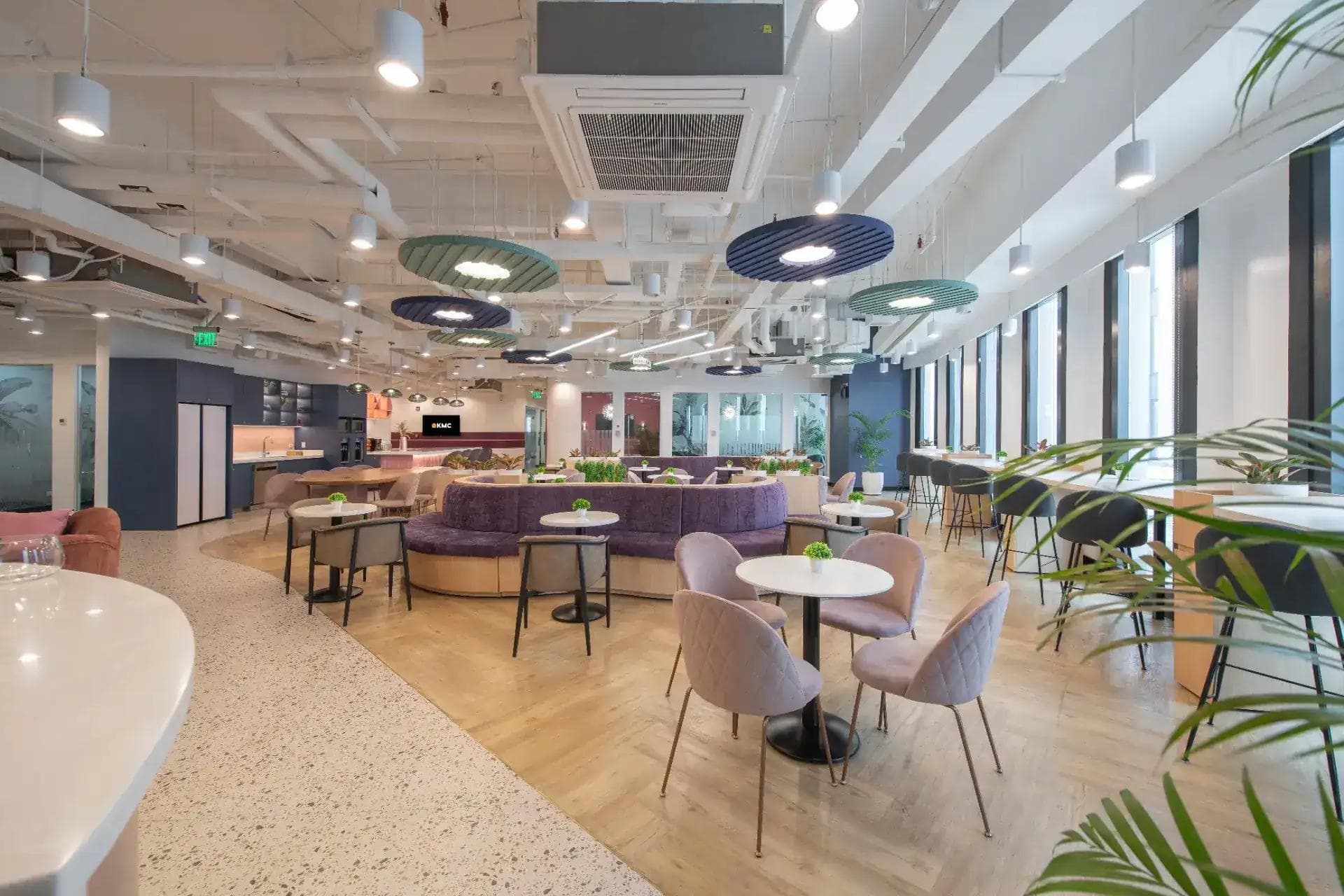 Bright coworking space in Quezon City with round tables, wood floors, and ceiling lights in a modern open-plan layout.