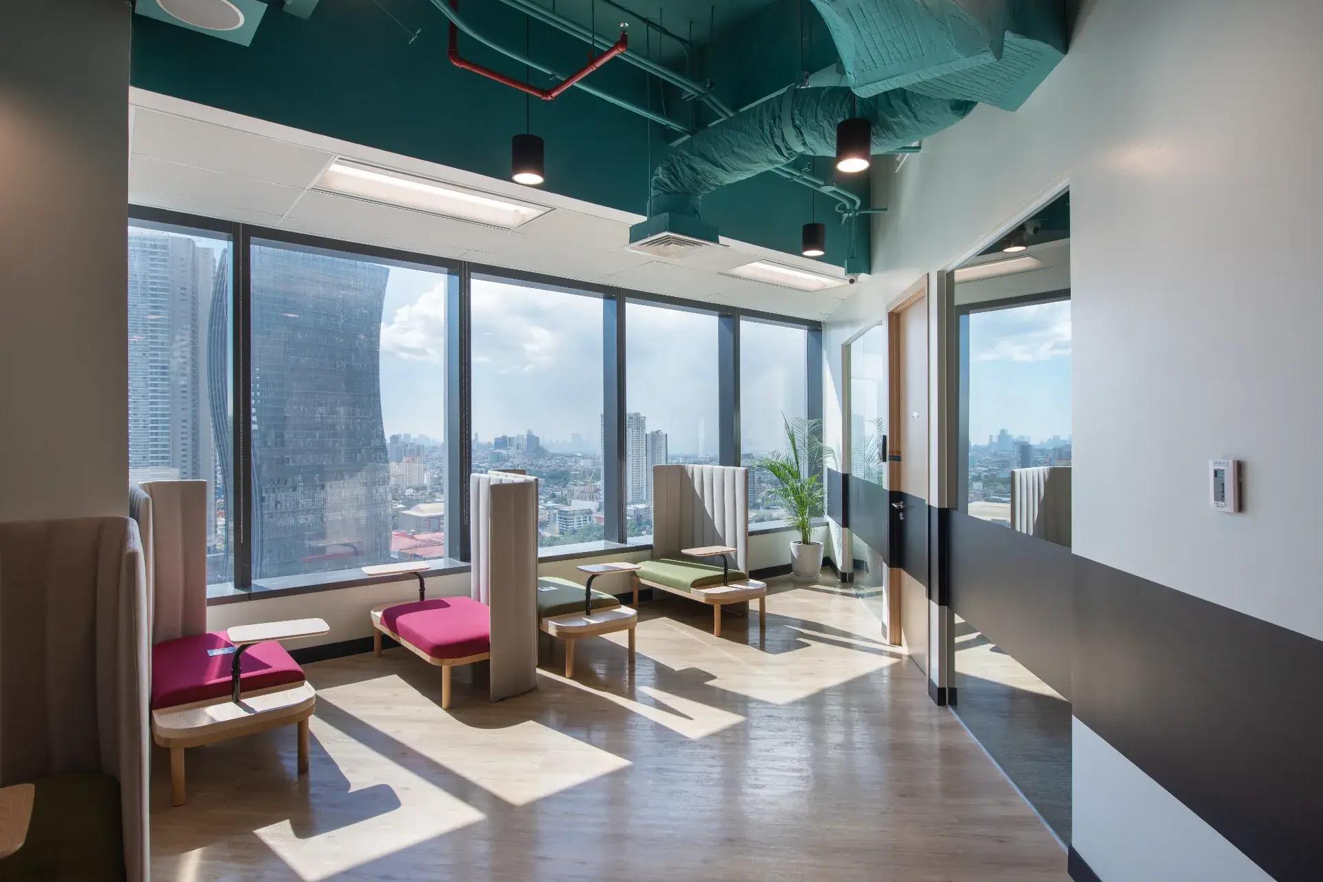 A Mandaluyong office space with cozy seating, bright natural light, wooden floors, and panoramic city views. A Mandaluyong office space with cozy seating, bright natural light, wooden floors, and panoramic city views.