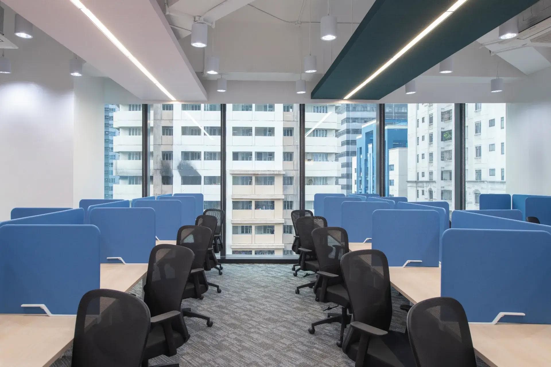 Modern KMC coworking space in Pasig with blue dividers, natural lighting, carpeted floors and ergonomic chairs.
