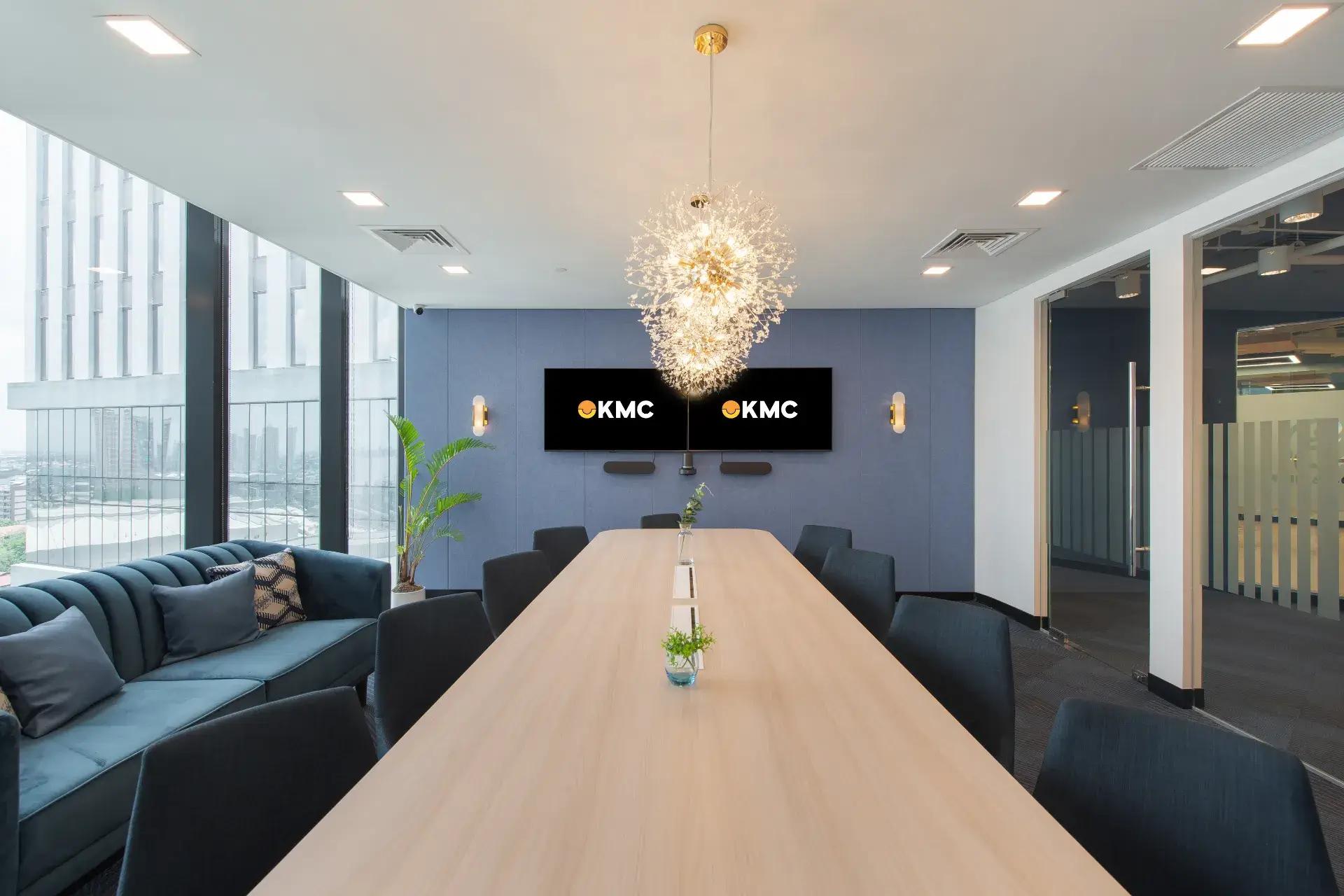Elegant meeting room with a wooden table, a cozy teal couch, modern chandeliers and floor-to-ceiling windows with city views. Elegant meeting room with a wooden table, a cozy teal couch, modern chandeliers and floor-to-ceiling windows with city views.