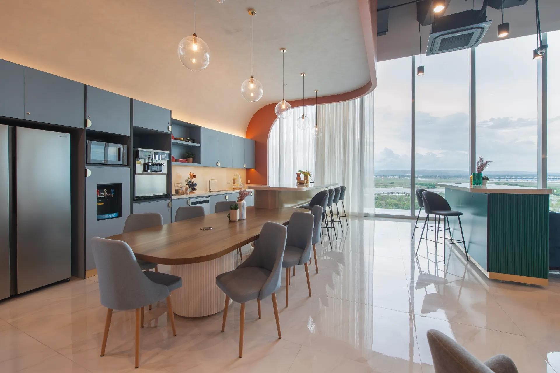 Modern KMC pantry in Clark with a long wooden island, built-in appliances, and floor-to-ceiling windows overlooking the city.