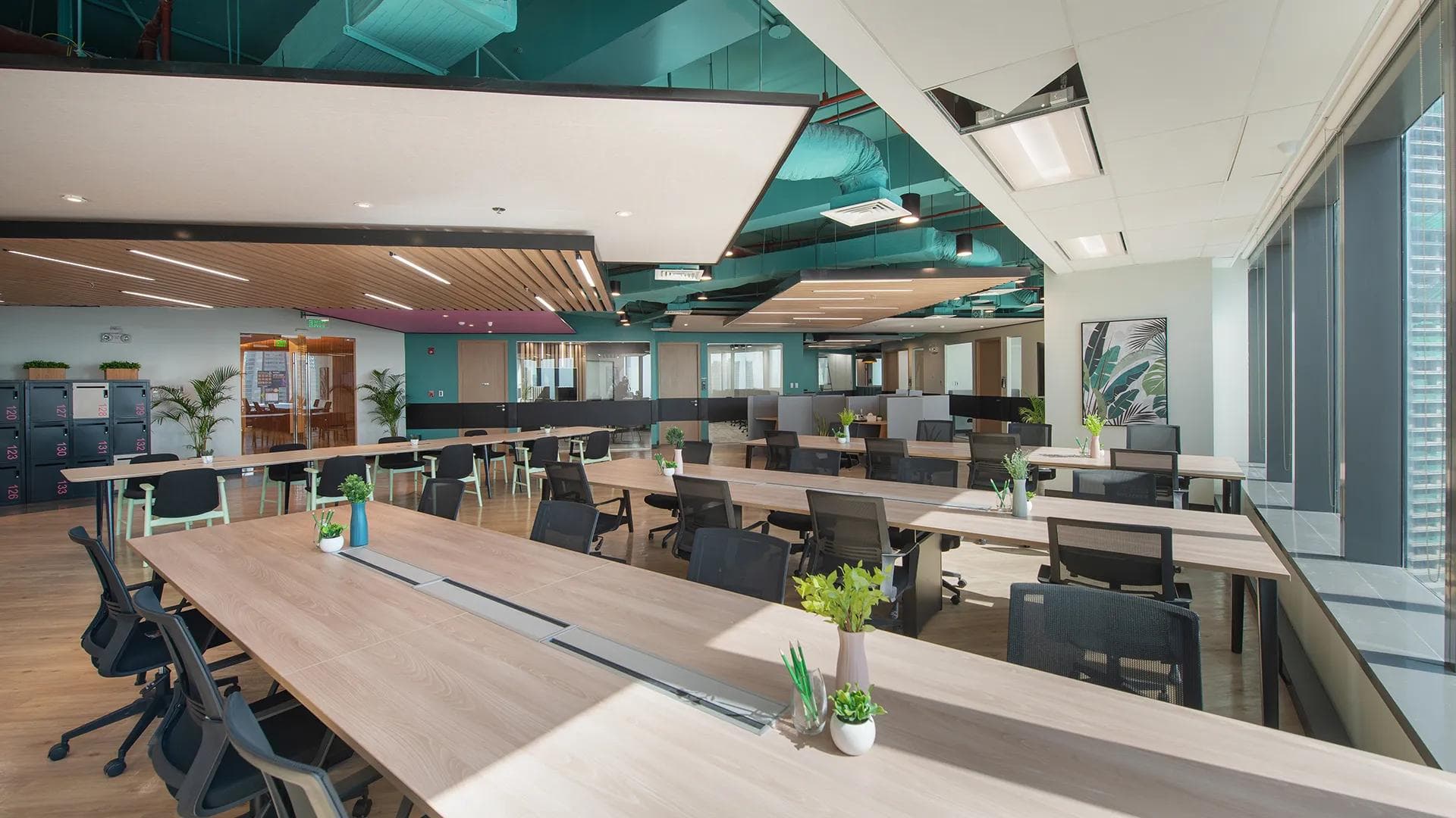 Spacious open-plan KMC workspace in BGC with shared desks, ergonomic chairs, and floor-to-ceiling windows.